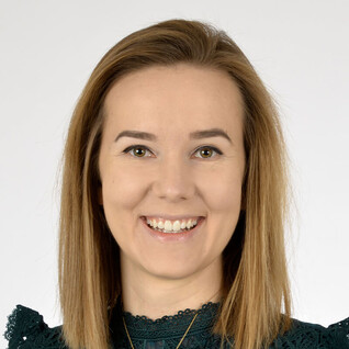 Portrait einer Frau mit mittellangen Haaren, die freundlich in die Kamera blickt.